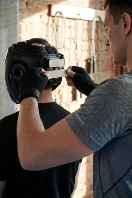 Persona ajustando las correas traseras de un casco de boxeo