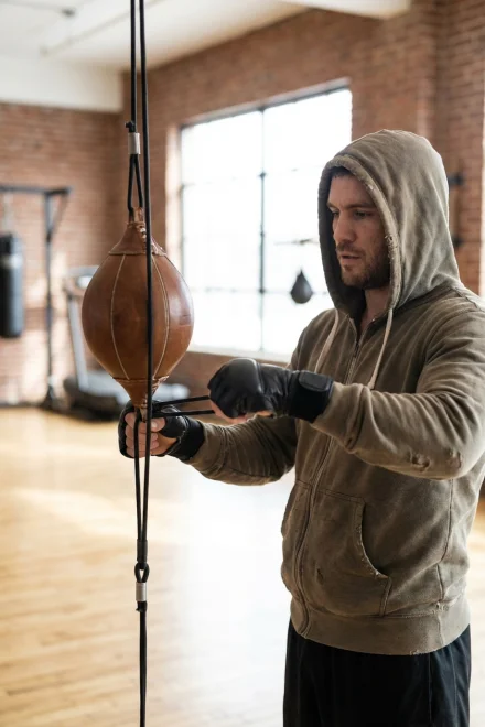 Pugile che regola le corde elastiche di un sacco a doppia estremità