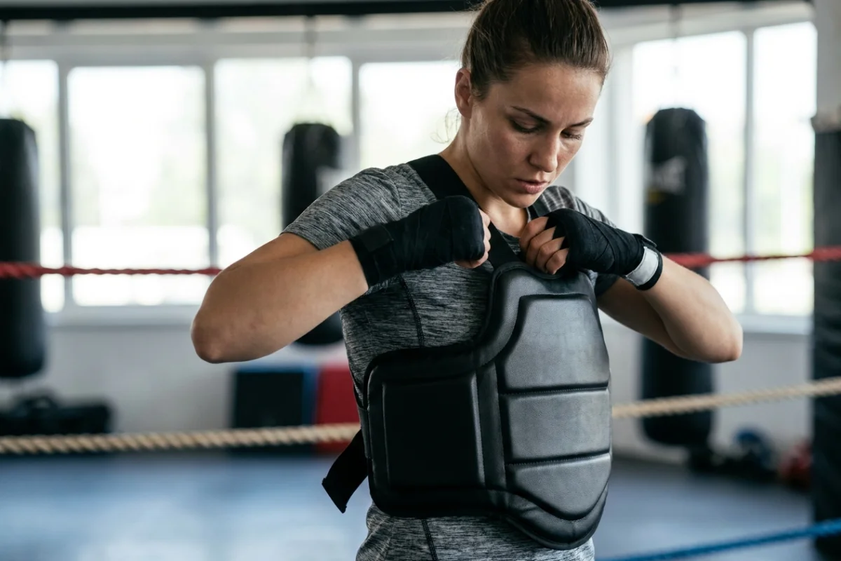 Female boxer adjusting a professional chest protector for contact training