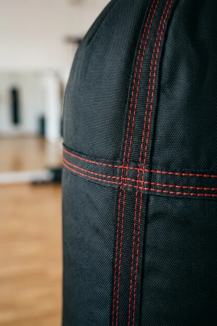 Detalhe de costuras reforçadas e material de nylon num saco de boxe profissional